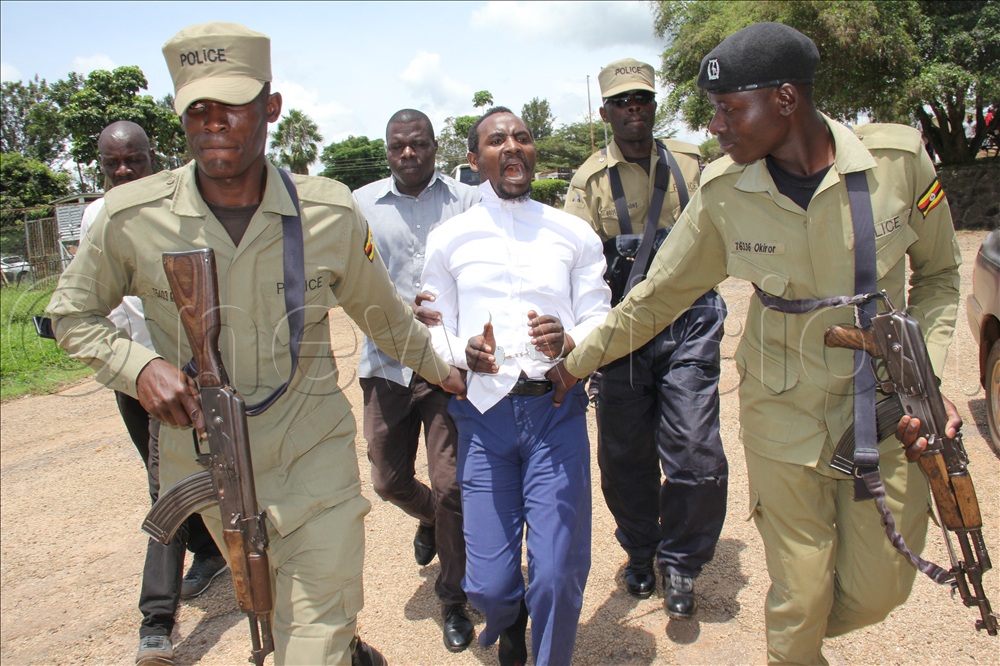Rev. Moses Atuhaire (in white shirt) being taken to Police.