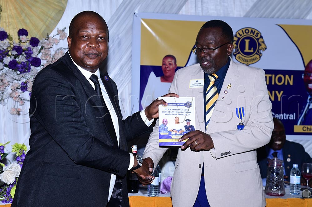 AIGP Moses Kafeero receiving a souvenir magazine for the installation of Dr Alungat from Dans Naturinda, the leader of the Lions. (Credit: Godfrey Ojore)