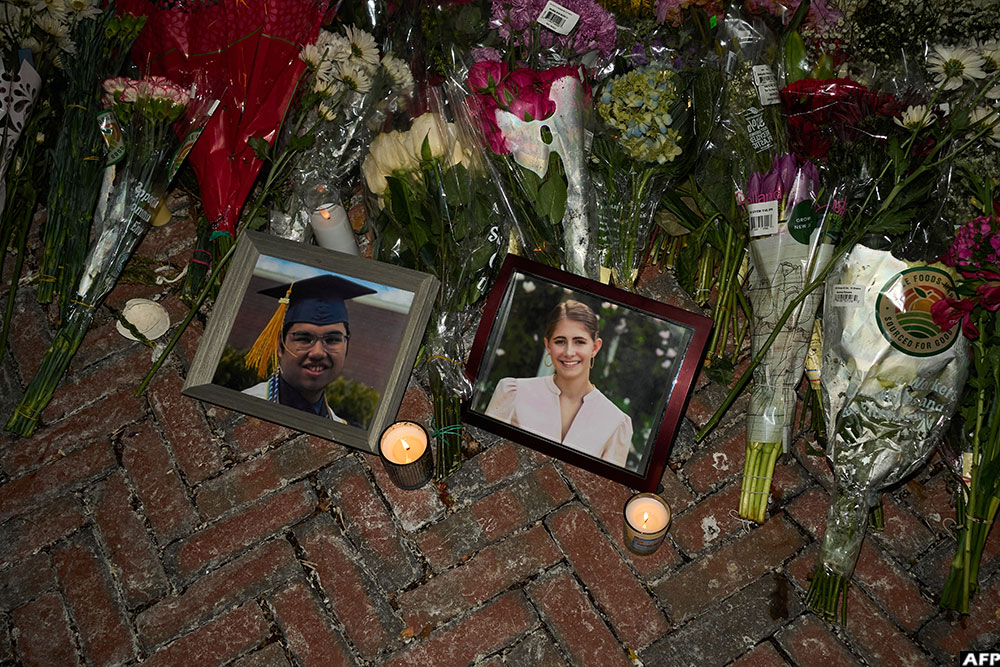 Candles are lit by framed photos of mass shooting victims Mukhammad Aziz Amurzokov and Ella Cook at a makeshift memorial near Brown University in Providence, Rhode Island, on December 15, 2025