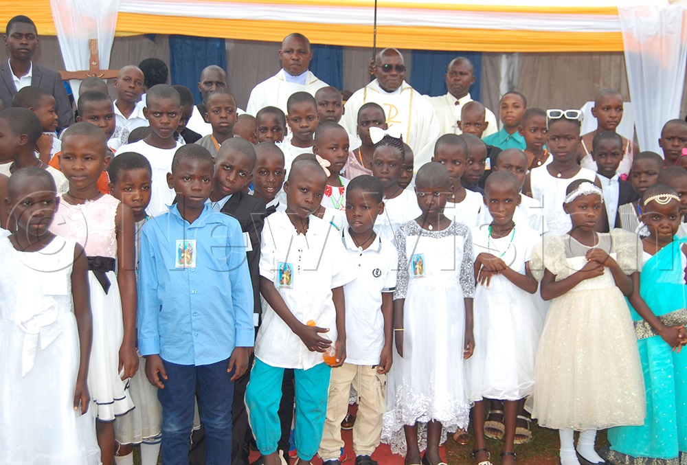The children who received first Holy Communion share a photo-moment with the clerics after mass. (Photo by Mathias Mazinga)