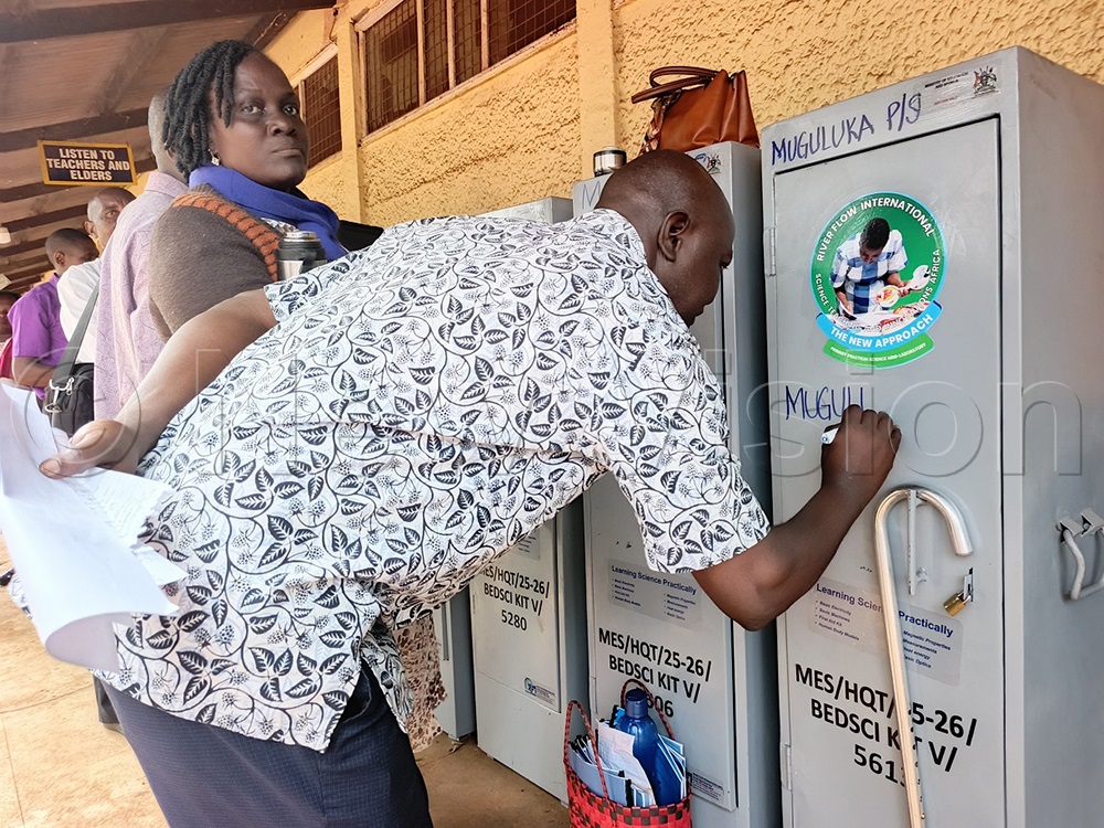 George Musenze, the head teacher Muguluka P/S, in Buwenge sub-county marking the cabin containing the donated science kits at Mwiri P/S in Jinja district on Monday. (Photo by Jackie Nambogga)