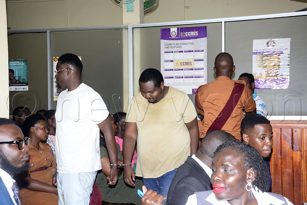 Pius Mwiru Mbunga and Samuel Karanja being escorted out of court, where they were charged with illegal entry and stay in Uganda. (Photo by Margret Zalwango)