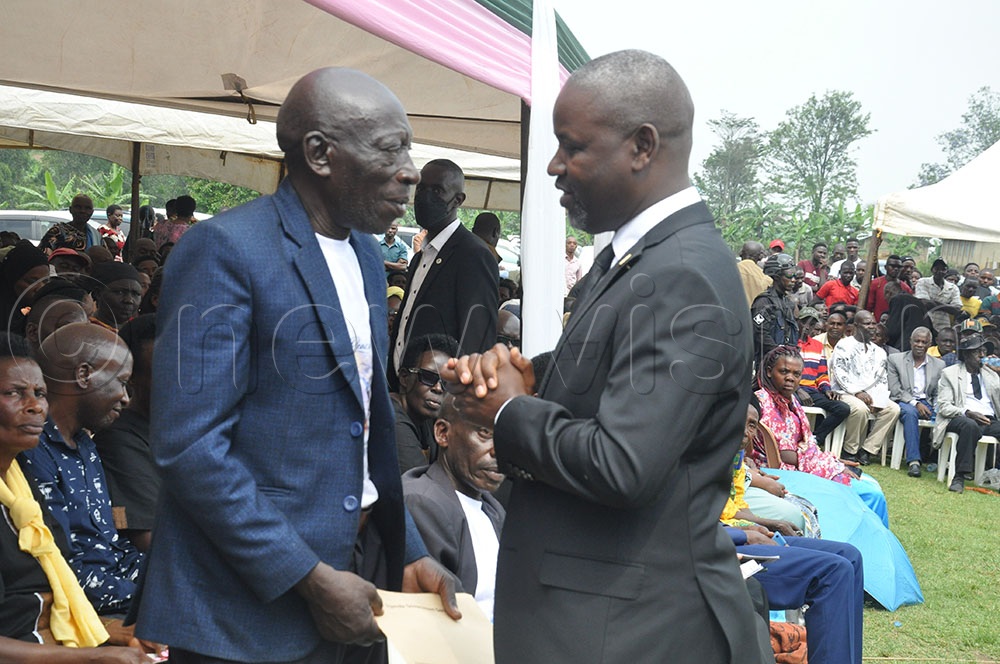 Deputy Speaker Thomas Tayebwa interacts with the heir of the late George Kanyarwanda during the burial ceremony. (Credit: Bruno Mugizi)