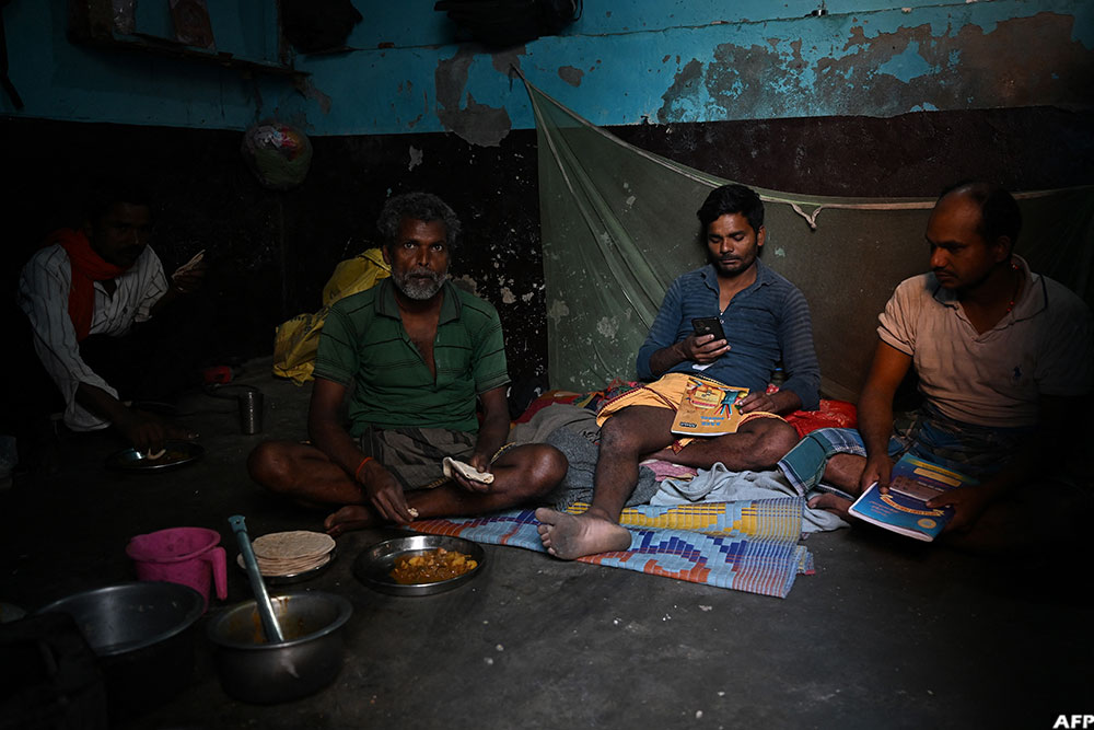 Migrant workers sit inside their rented room in New Delhi