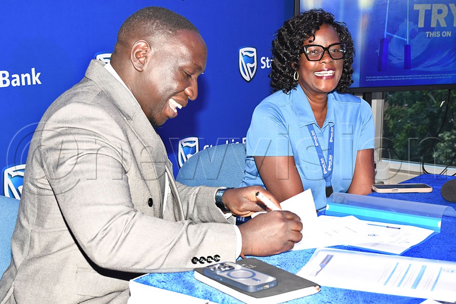 Daniel Canowira (left) the Black Pirates chairman signs a three-year partnership contract as Rita Apell, the Stanbic Chief Information Officer looks on at Stanbic offices in Kampala. Photo by Michael Nsubuga