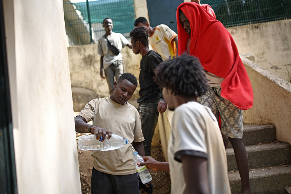Migrants collect water outside the CETI short-stay migrant centre in the Spanish North African enclave of Ceuta on August 1, 2026.