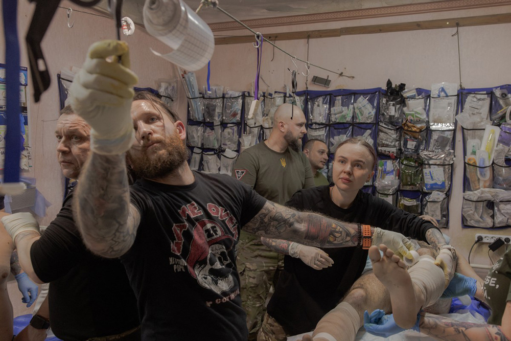 Ukrainian combat medic Anastasia Podobailo (R), with her colleague and husband Mykola Yasinenko (2nd L) and other military medics treat an injured soldier of the Ukrainian army, at a stabilisation point of the 56th brigade, in the eastern Donetsk region, on March 15, 2026, amid the Russian invasion of Ukraine. (Photo by Roman PILIPEY / AFP)