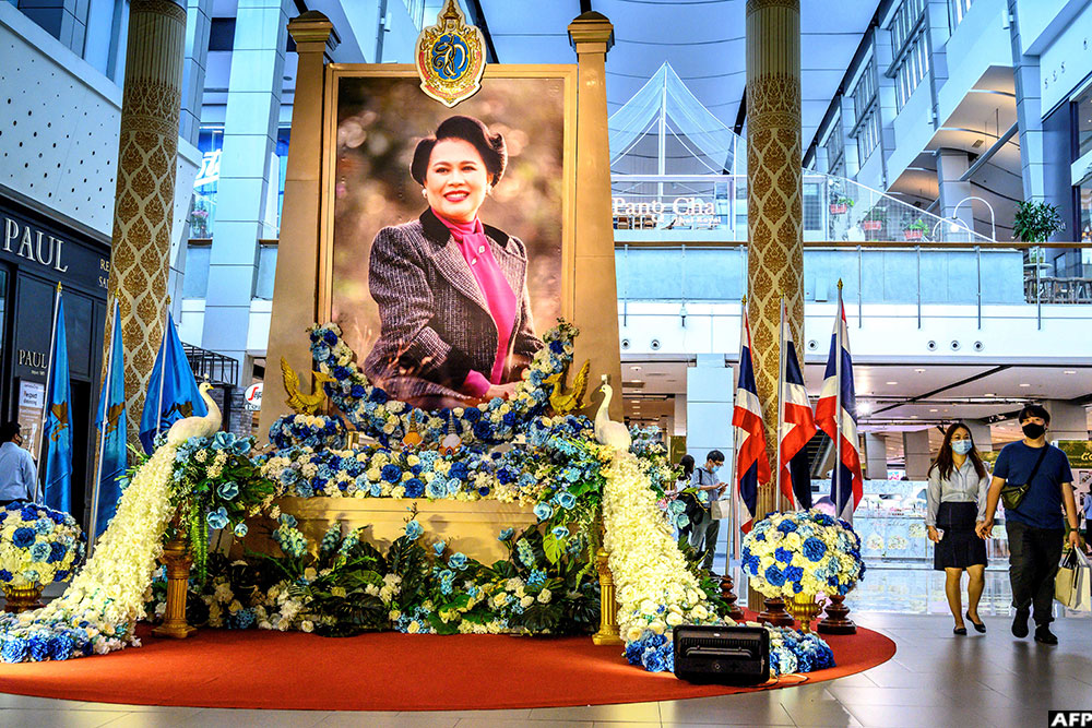 A couple walks next to a floral display created to mark Thailand's Queen Mother Sirikit's 88th birthday in a shopping mall in Bangkok on August 11, 2020. (AFP)