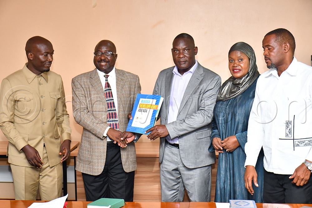 The former L.C V chairperson of Mayuge district and former BCD Governor Bishop Frank Tibagendeka (2nd L) handing over a Busoga Development Agenda booklet to the Bugiri district L.C V chairperson and newly elected BCD Governor Davidson Mulumba Kasajja (C) as Busoga Consortium for Development's Director General Anthony Mula (L), 3rd Deputy Prime Minister Rukia Nakadama (2nd R) and Iganga district L.C V chairperson and BCD Vice Governor Shabiru Isabirye (R) witness. (Photo by Donald Kiirya)