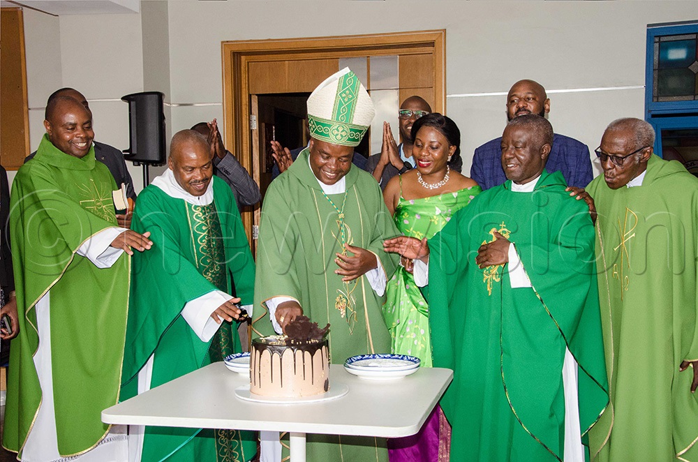 Archbishop of Mbarara, His Grace Lambert Bainomugisha (Centre), Catholic clerics and Centenary Bank Staff cut a cake. (Photo by Colleb Mugume)