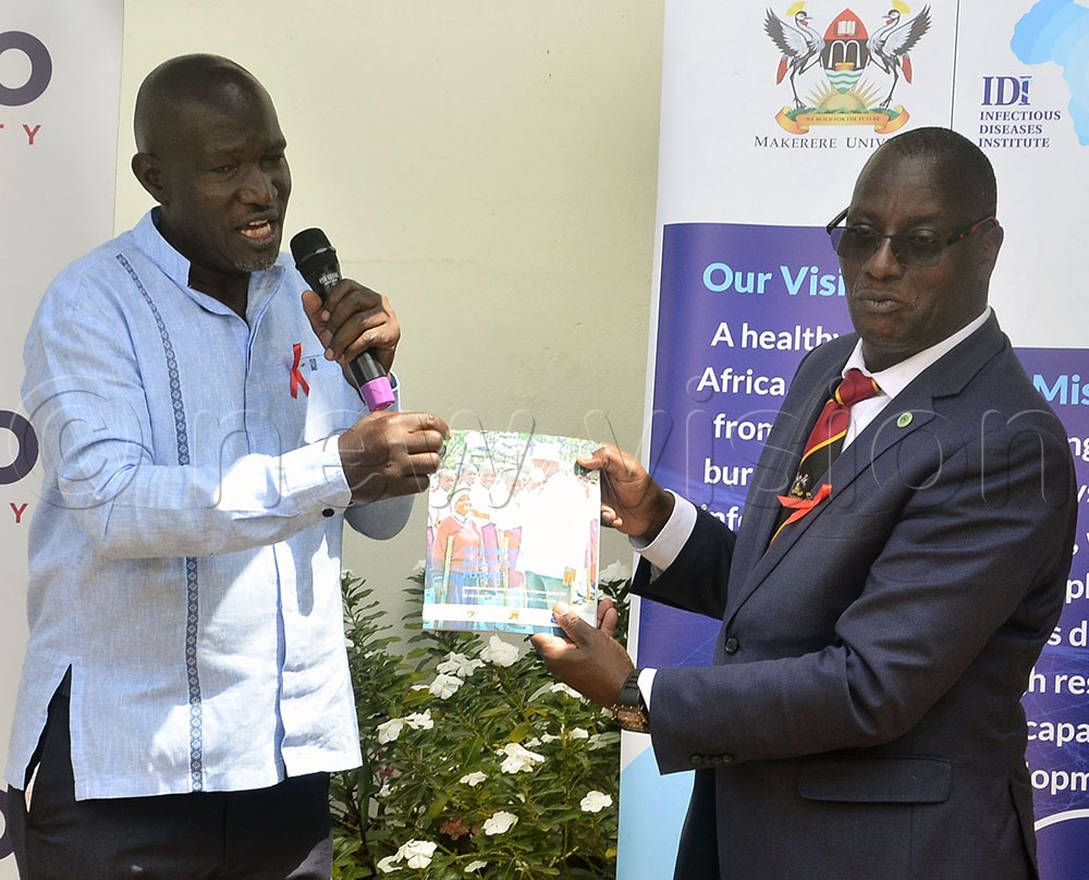 Dr Shaban Mugerwa, the Equity Plan Coordinator at the Uganda AIDS Commission, hands over a copy of the book titled Building a Brighter Future to IDI Director Dr. Andrew Kambugu during World AIDS Day at the IDI offices in Mulago. (Credit: Juliet Waiswa)