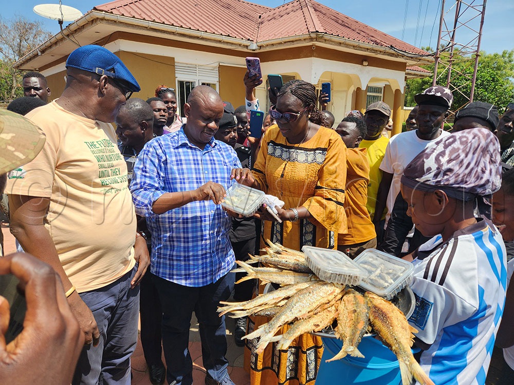 Balaam Barugahara the minister of Local governments in company of Godfrey Marshall Alenyo the member of parliament for Jonam County and Pakwach Woman MP Jane Avur Pacuto trying out Onanga nang fish packed in containers. This was during the minister’s tour of the district during his anti-corruption crusade in the district on August 13, 2026. (Credit: Lawrence Mulondo)