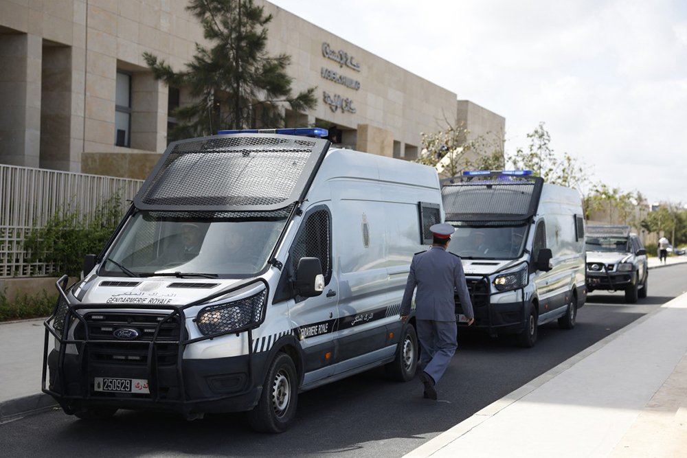 A police officer walks past police vans believed to be transporting Senegalese detainees outside the Rabat Court of Appeal on April 13, 2026. (AFP)