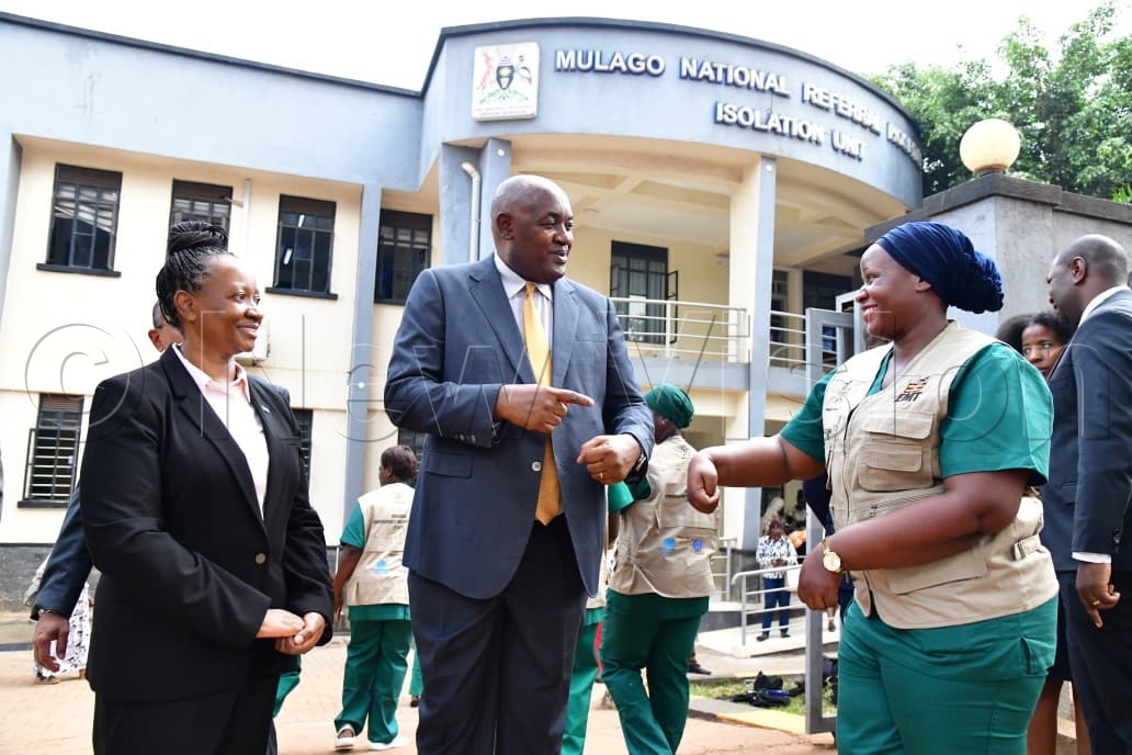 Health Minister Dr Chris Baryomunsi interacts with Rehema Kobusingye, a nursing officer at the Mulago Isolation Unit. (Credit: Mpalanyi Ssentongo)