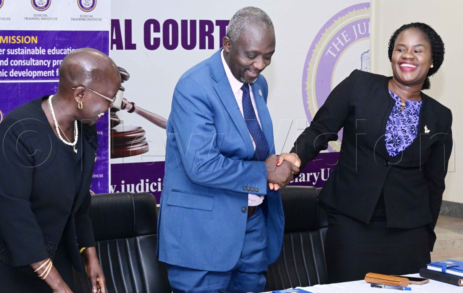 Hon. Justice Prof. Andrew Khaukha (Centre) shaking hands with Pamela Lamunu (Right).