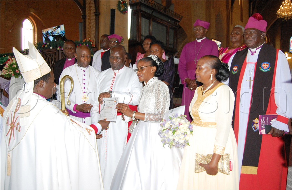 The Bishop of Namirembe diocese, Moses Banja (wearing a mitre) hands over to the Kiwanukas their 25th wedding anniversary certificate after the wedding service at Namirembe Cathedral on December 30, 2025. Looking on are some Anglican Prelates and their spouse.