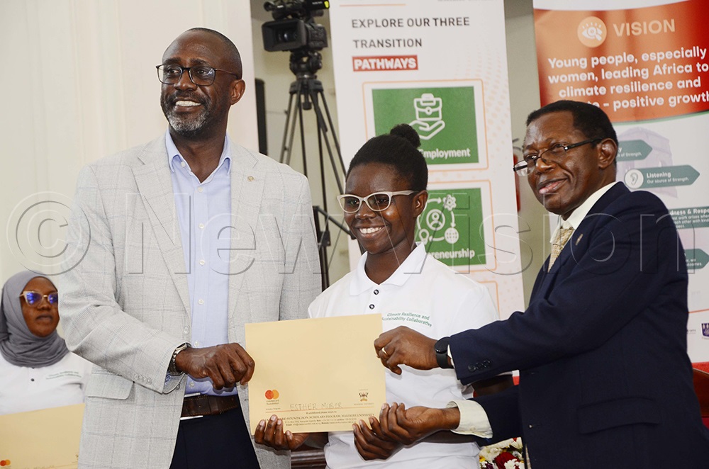 Adrian Bukenya, Mastercard Foundation Uganda country director hands over the scholarship award to Esther Muber as Prof. Buyinza Mukadasi, Deputy VC academic affairs look on during the scholarship award ceremony at Makerere University on September 11, 2025. (Photo by Juliet Kasirye)