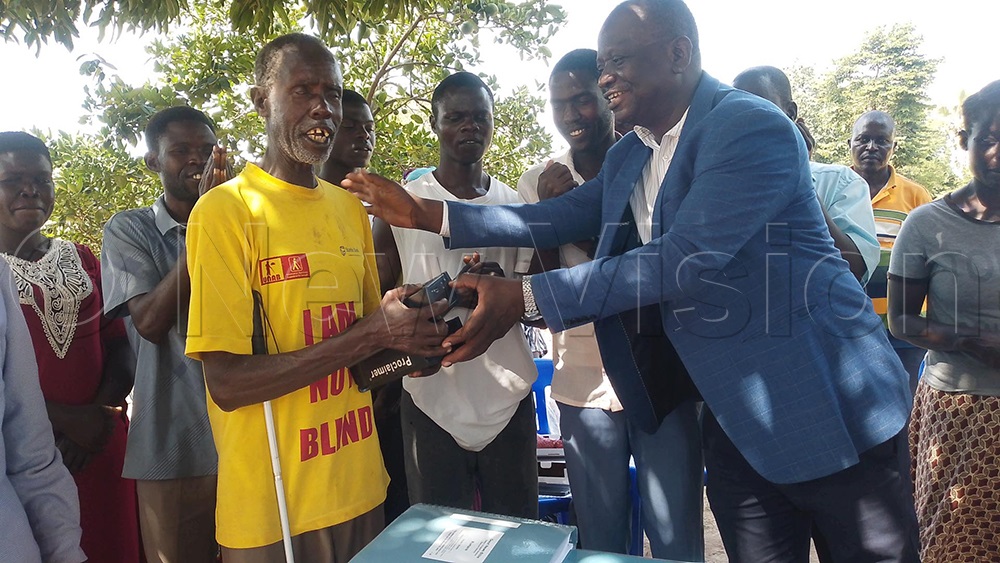 Pastor Abraham Okurut handing over an audio bible to Okurut and his family. (Photo by Godfrey Ojore)