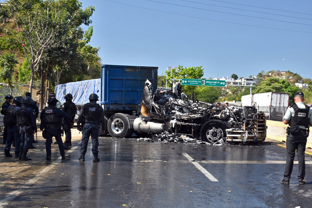 Firefighters extinguish the fire of a truck that was set on fire on a street in the port of Acapulco, Guerrero state on February 22, 2026. (Credit: AFP)