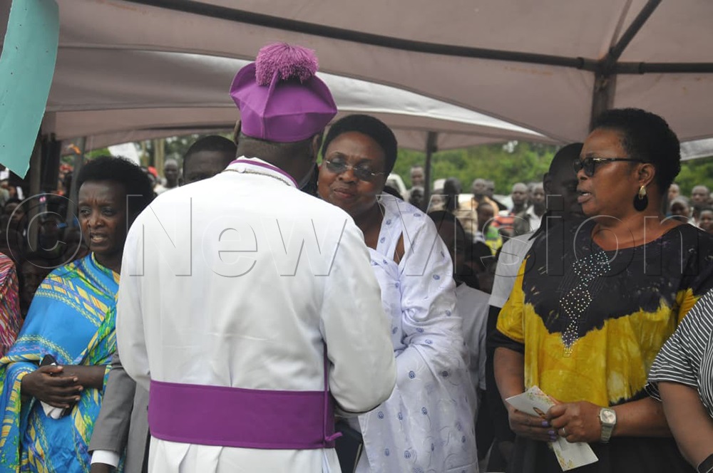 Bishop Twinomujuni consoles the widow during the burial. (Photo by Bruno Mugizi)