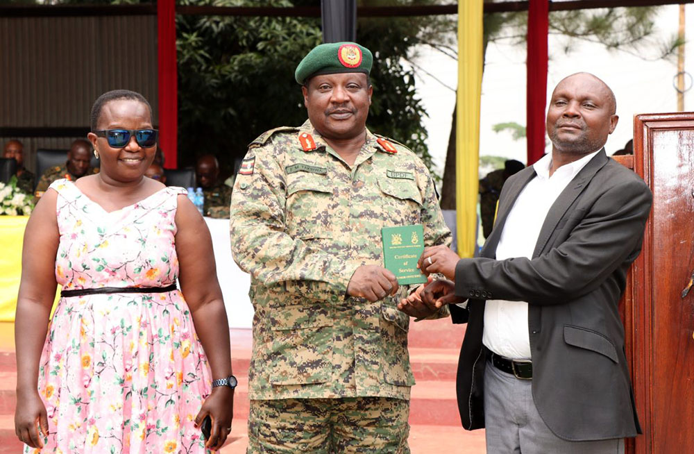 Deputy Commander Land Forces Maj. Gen. Francis Takirwa awarding a retiree a certificate during the discharge of Junior officers and other ranks. (Credit: UPDF)
