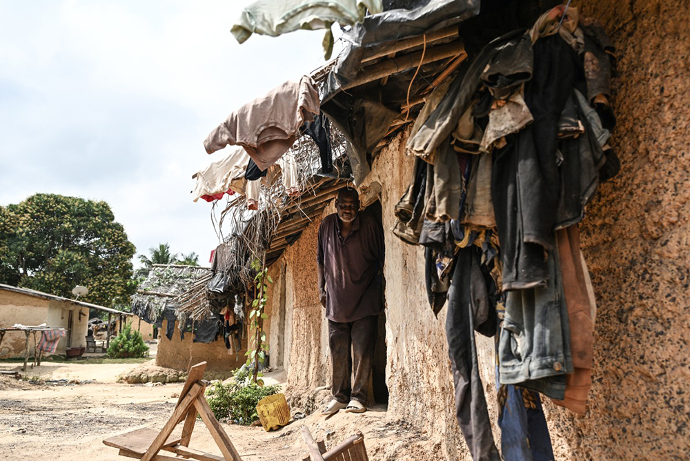 Boniface Djabia, the chief of Betykro, a camp of cocoa producers living in precarious conditions 20 km from Guiglo, poses for a portrait in front of one of his mud houses covered with straw on January 16, 2026. (AFP)