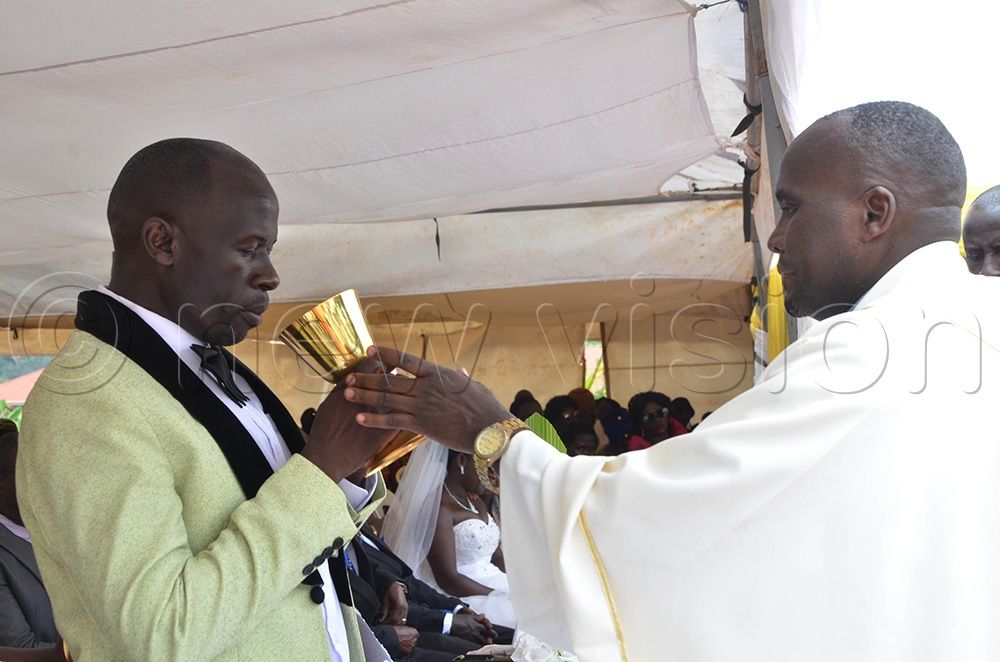 A groom receiving holy communion during the wedding ceremony for at St Padre-Pio Catholic Parish Kabulamuliro on Saturday in the Mass wedding organised by Entebbe Deanery Catholic Charismatic Renewal. (Photo by Juliet Anna Lukwago)