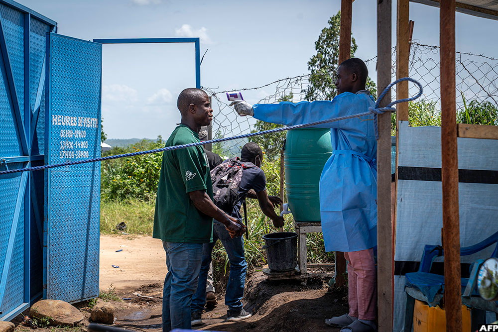 A healthcare worker takes a visitor's temperature at Rwampara Hospital in Ituri