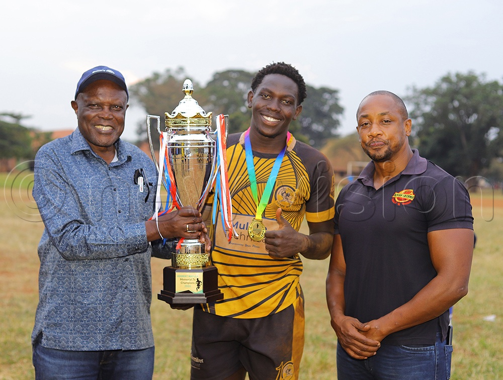 Former Rugby Union Chairman Paul Sigombe (L) hands over the trophy to Walukuba Barbarians team captain as former team mate with Wafula Ebra Nyango looks on right. (Photo by John Were)