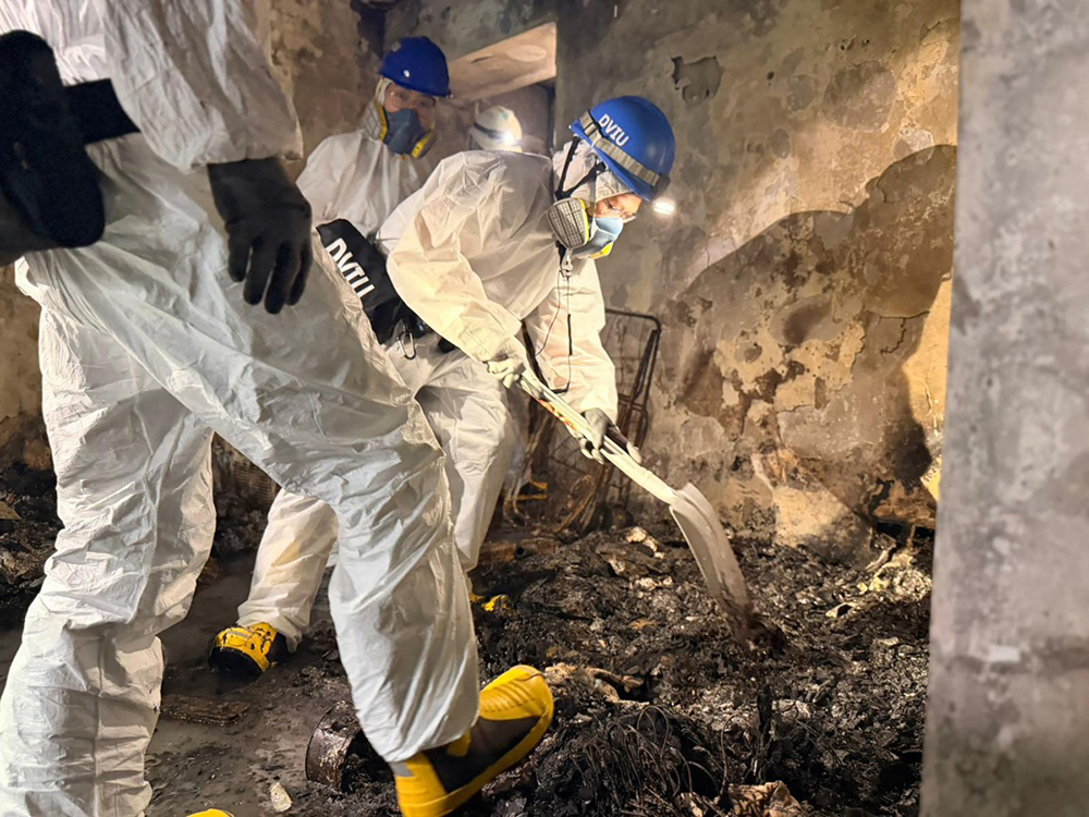 This handout photo released by the Hong Kong Police Force on November 30, 2025 shows officers from the Disaster Victims Identification Unit (DVIU) working inside an apartment block in the aftermath of a fire at the Wang Fuk Court residential estate in Hong Kong's Tai Po district. 