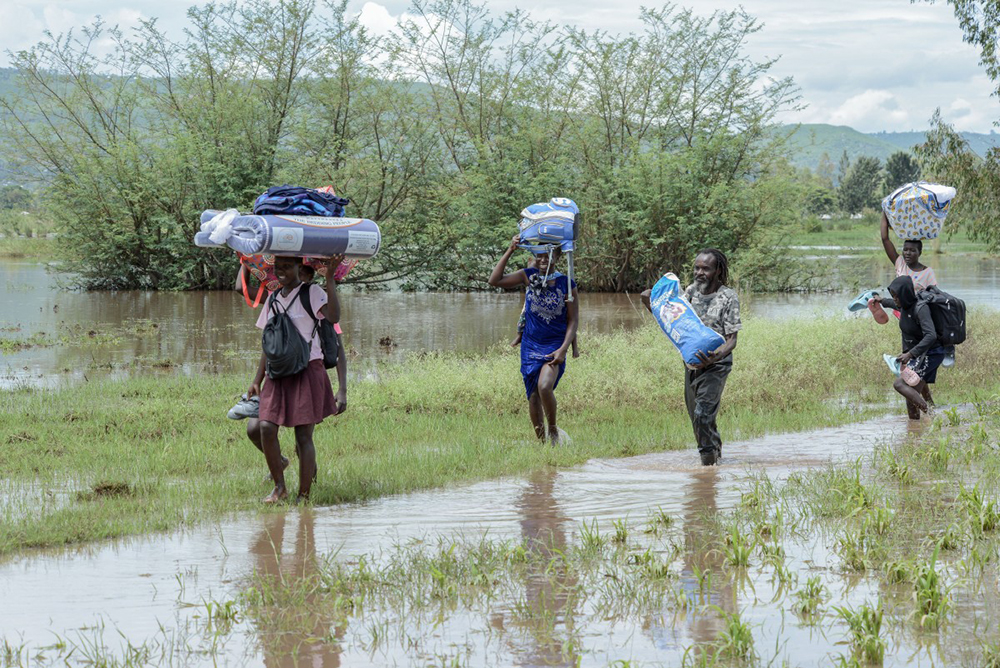 Residents carry their belongings as they walk through a flooded area in West Nyakach, Kisumu County, on March 22, 2026.