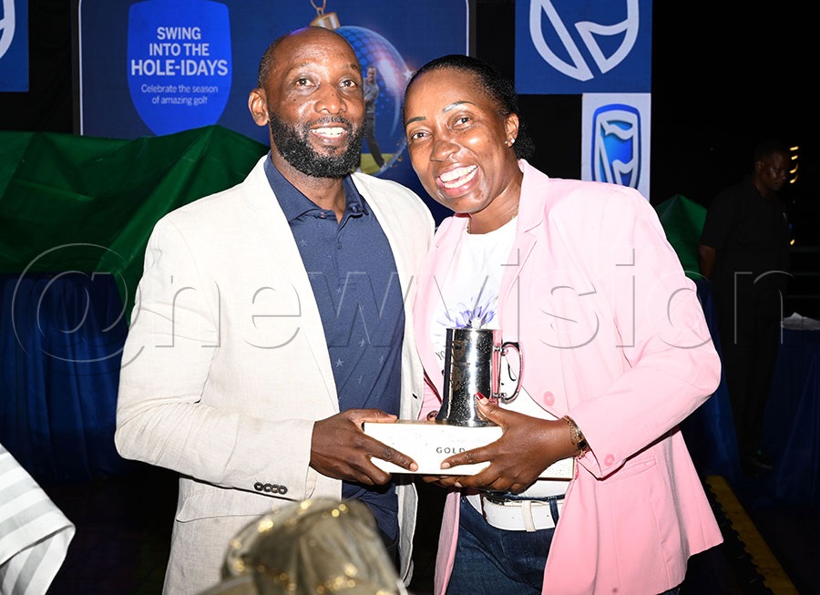 Stanbic Bank Head of Affluent Clients Arthur Kiwanuka (left) hands over a mug to Gloria Mbaguta. Photo by Michael Nsubuga