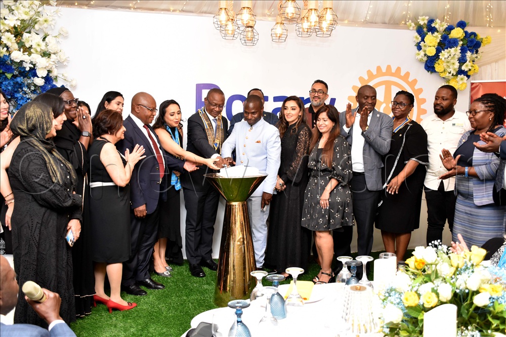 Geoffrey M. Kitakule, the rotary district governor of D9213 (centre) cutting a cake with Rotarians from the rotary club of Kololo summit view shortly after chartering their club. 