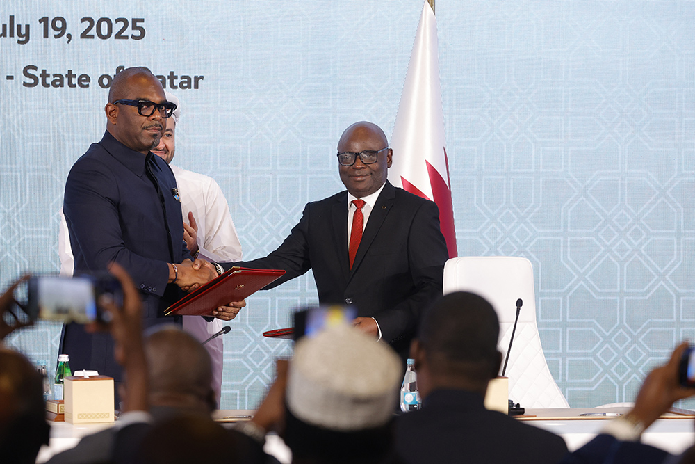Peace mediator Sumbu Sita Mambu, a high representative of the head of state in the Democratic Republic of Congo (L), and Rwanda-backed armed group M23 executive secretary Benjamin Mbonimpa (R) shake hands after signing a ceasefire deal in the Qatari capital Doha on July 19, 2025. (Photo by Karim JAAFAR / AFP)
