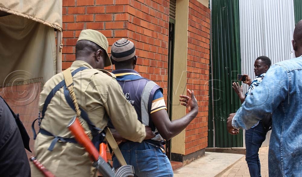 A police officer takes Juma Magumba, one of the alleged abductees' brothers, who was trying to rescue the suspect. (Credit: Eric Yiga)