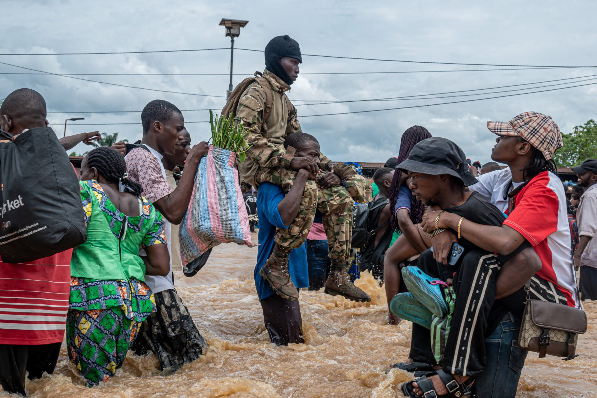 A resident carries a Congolese soldier as others wade through floodwaters in the Ndjili district of Kinshasa.