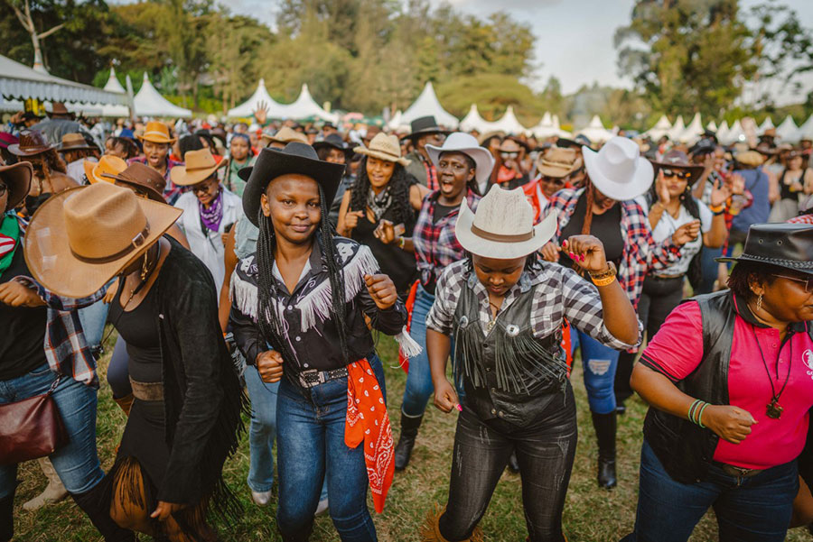 Revellers line dance during the International Cowboy Day at Ngong race course in Nairobi on July 26, 2025. Country music have a loyal fan base in Kenya and the popularity of the music continuing to grow, the event was celebrated by hundreds of attendees with a collective of country artists performing.  The headline of the event was Sir Elvis, Kenya's biggest country star. AFP PHOTO
