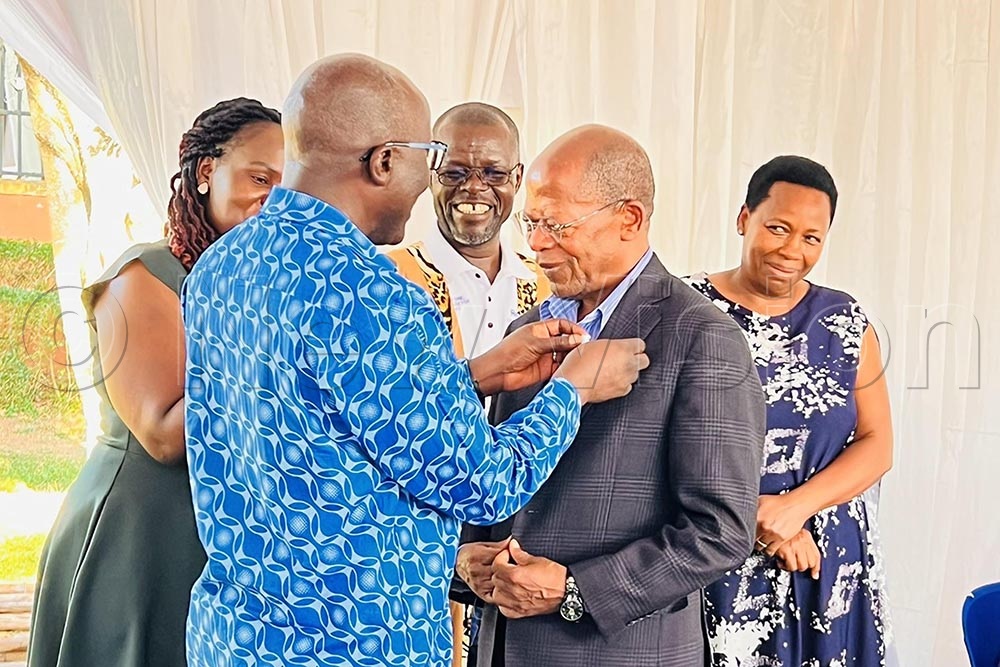 District Governor D9214 decorating Acting Minister of Education Dr. John Chrysestom Muyingo as her wife Rose Namayanja Muyingo looks on. (Credit: Isaac Nuwagaba)