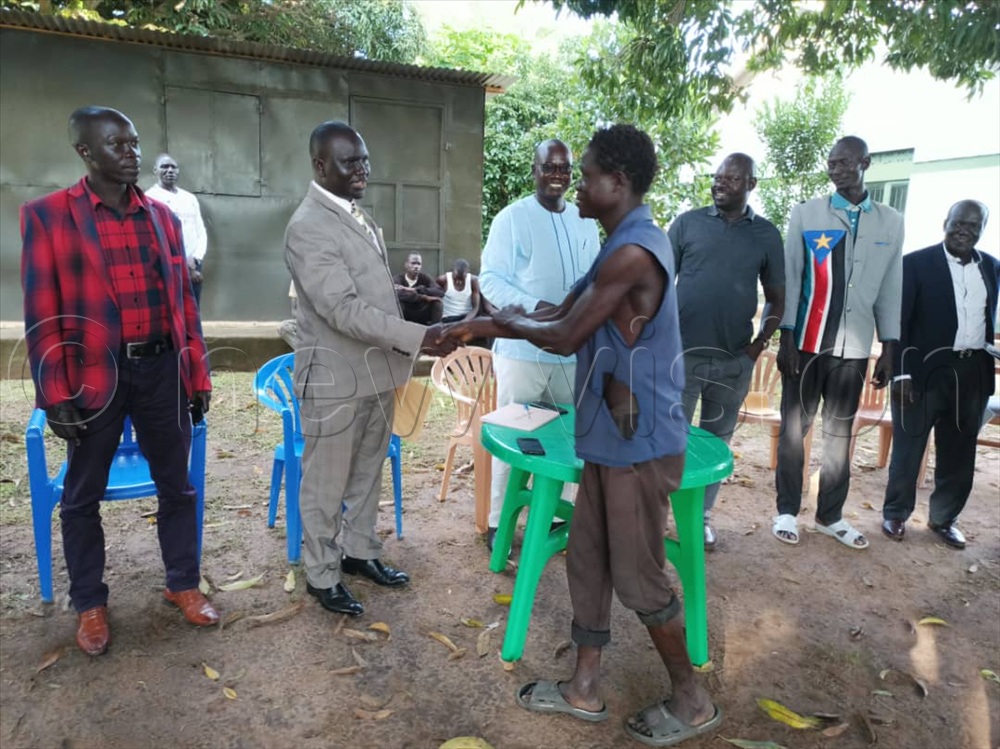 Asiku ( left) shaking hands with one of the 13 arrested Ugandans after their release at Afogi border customs in Moyo district on Thursday.