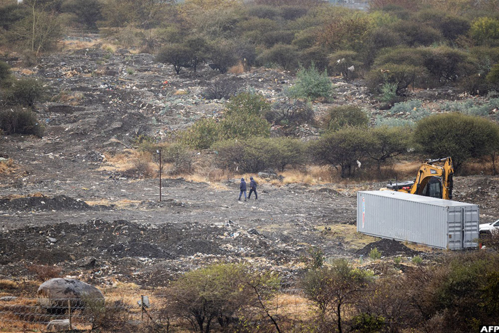 SAPS officers walk on near a mine shaft in Nkaneng near Marikana on August 11, 2026, where 14 illegal miners were found dead