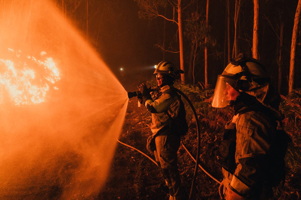 Members of the XVII and XVIII Galician forest firefighting brigades work through the night to control a wildfire in Oia, Pontevedra, Galicia, Spain on August 22, 2025.