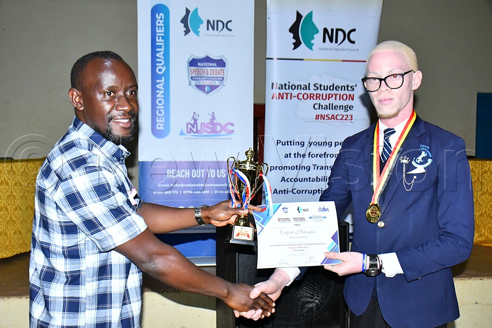Busoga College Mwiri's Israel Galandi (right) receives his certificate from Saleh (left), patron of the Budini Secondary School Debate Club, during the 11th Kiira/Busoga Regional Speech and Debate Qualifiers at Busoga College Mwiri in Jinja District on July 12, 2026. (Photo by Donald Kiirya)