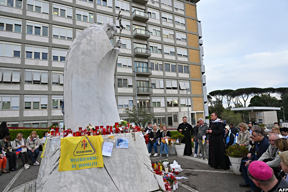 Faithfuls, priests and nuns pray at the statue of John Paul II outside the Gemelli University Hospital where Pope Francis is hospitalised in Rome on March 11, 2025. (AFP)