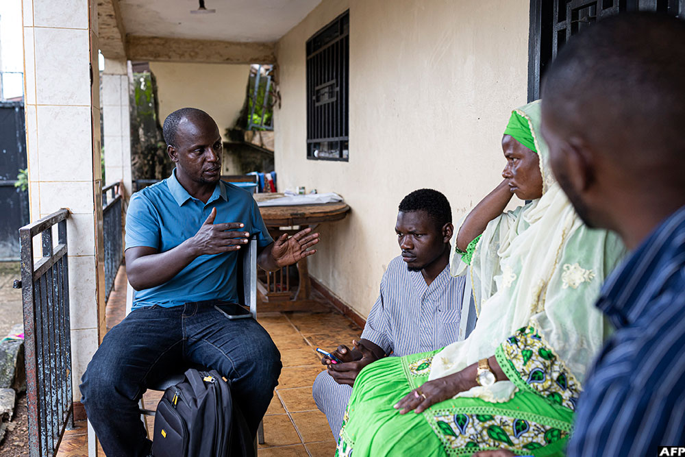 Guinean Organization for the Fight Against Illegal Migration (OGLMI) executive director Elhadj Mohamed Diallo (L) speaks with Tahibou Diallo (2nd R), mother of Thierno Mouctar, and her son Thierno Sadou (2nd L) at their home in Conakry.