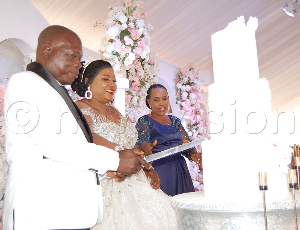 The Muwangas cut cake in celebration of their marriage. To the right is their matron, Grace Birungi. (Photo by Mathias Mazinga)