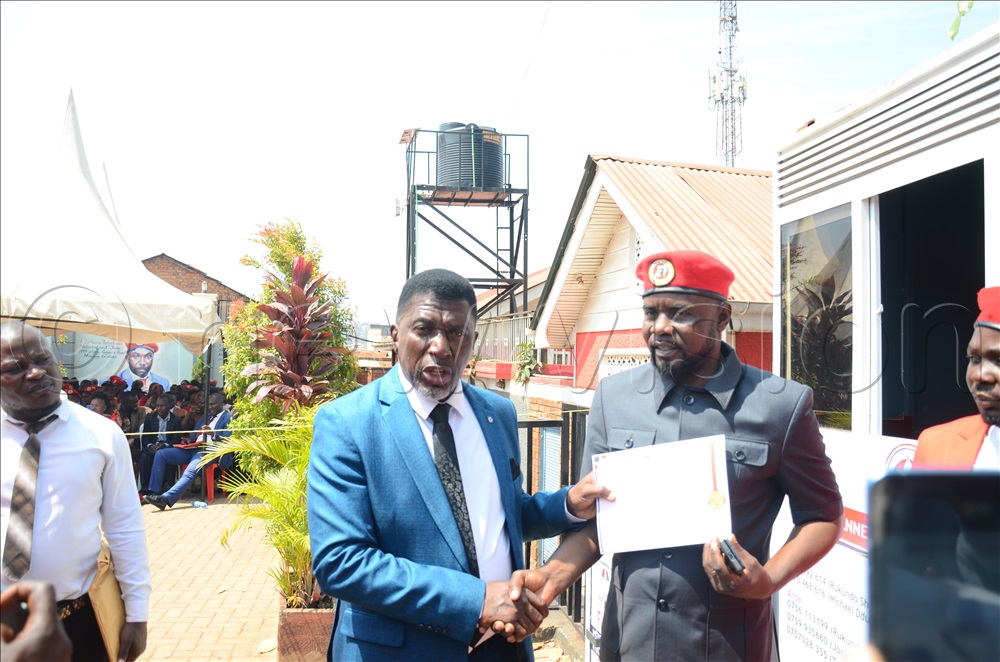 Mathias Walukagga, the Kyengera Town Council Mayor receiving a certificate from the NUP fundraising chairperson Ronald Balimwezo at Makerere Kavule.