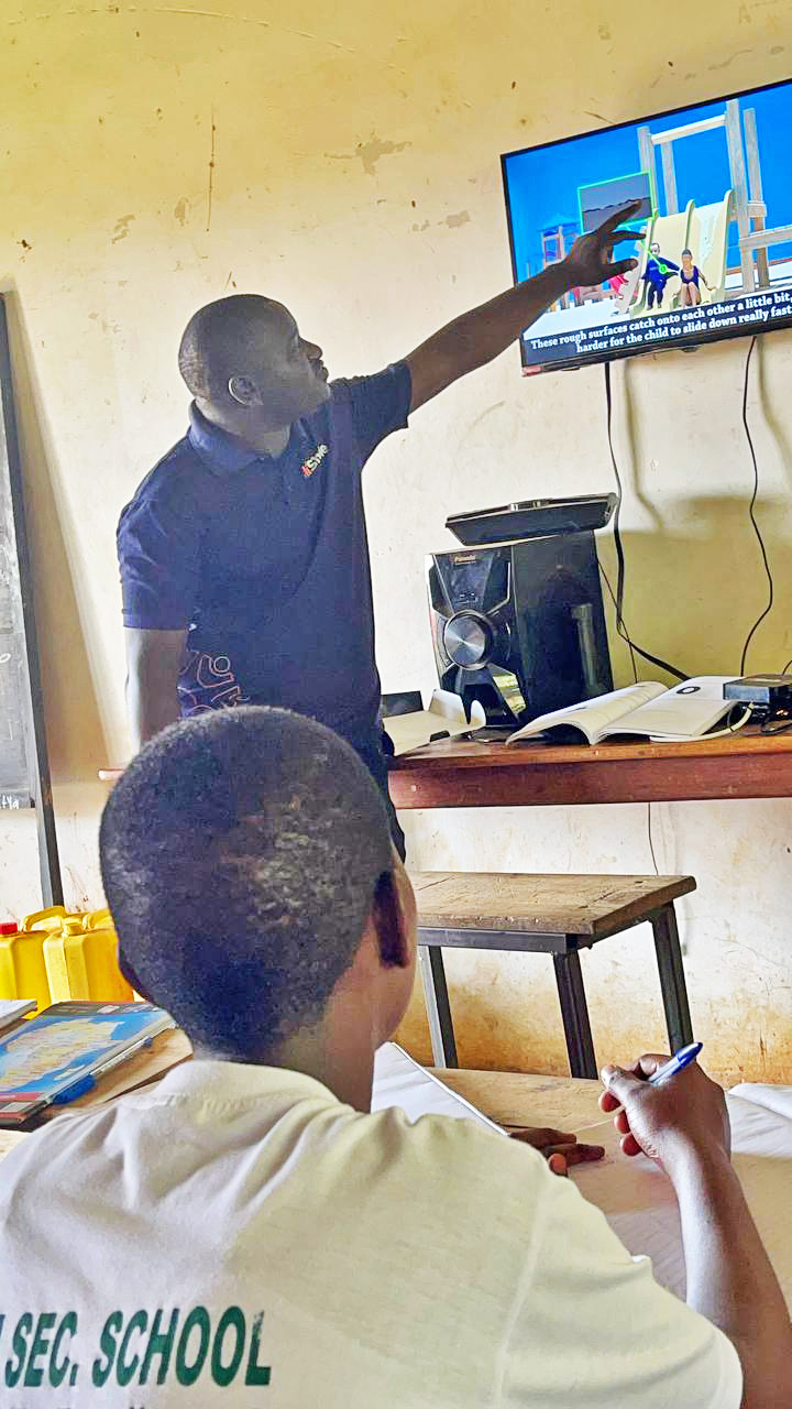 A student of Kawuku SS watching some of the content by Hishule as  Gideon Ssenkayi, the Team Lead (Hishule)  takes her through the lesson. (Courtesy photo)
