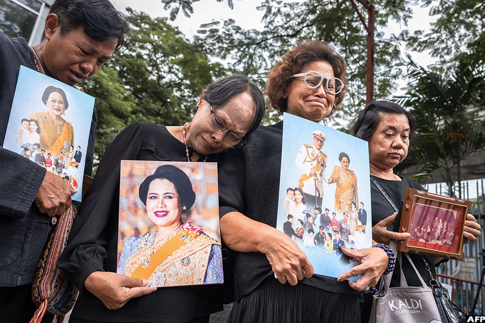 People hold portraits of Thailand's former Queen Sirikit as they gather in front of Chulalongkorn Hospital, where she passed away, in Bangkok on October 25, 2025.