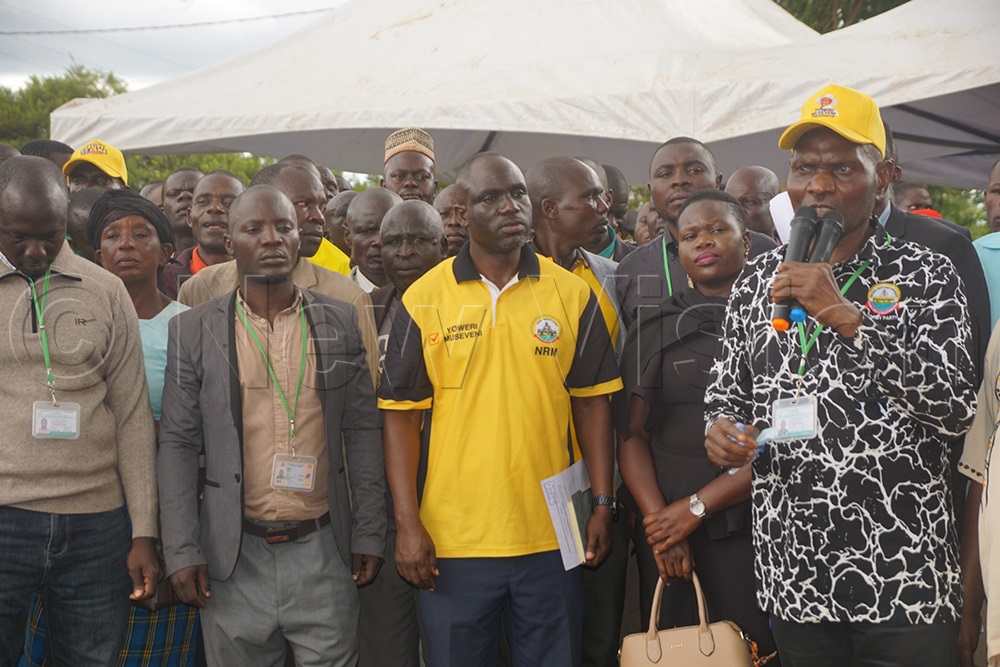 Patrick Mudhungu (with a mic) speaking during the meeting at Banda Secondary School. In the yellow T-shirt is the LC5 chairperson, Ronald Sanya, together with cane farmers. (Credit: Betty Angatai)