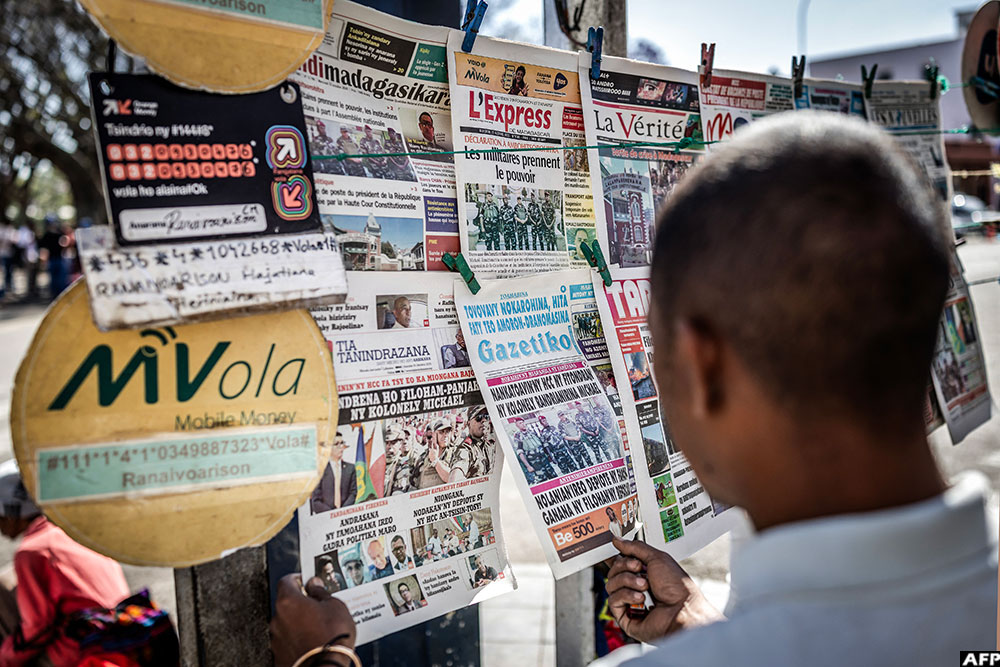 A resident reads newspapers at a newspaper stand displaying headlines about Madagascar’s military takeover